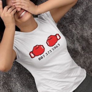 May include: White t-shirt with a pixelated image of two red boxing gloves and the text "007 373 5963".