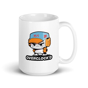 Puede incluir: Taza de cerámica blanca con un robot de dibujos animados que lleva una gorra de béisbol azul y naranja con texto japonés. El texto "OVERCLOCK'D" está impreso debajo del robot.