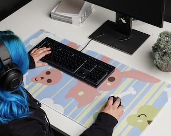 Puede incluir: Una persona usando un teclado y un ratón negros sobre una alfombrilla de escritorio colorida con un patrón a rayas e ilustraciones de animales de dibujos animados. La alfombrilla presenta un conejito rosa, una calavera y un pollito amarillo.