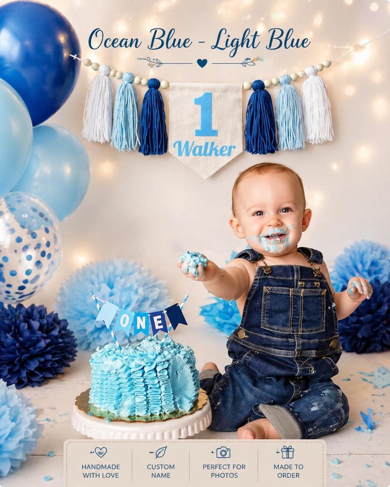 May include: A birthday decoration set featuring a banner with the text '1 Walker' and blue and white tassels, a blue cake topper with the text 'ONE', blue balloons, and blue paper pom-poms. The banner includes wooden beads and a heart icon.