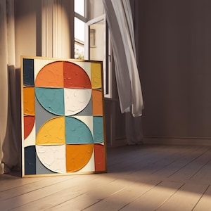 Puede incluir: Una obra de arte abstracta enmarcada con un marco dorado. La obra presenta un diseño geométrico con semicírculos y cuadrados en tonos de naranja, rojo, azul, blanco y amarillo. La obra está apoyada contra una pared en una habitación con suelo de madera.