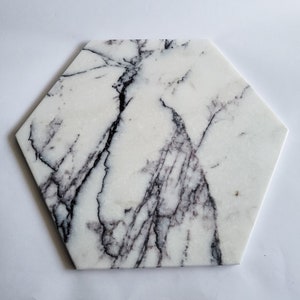 Può includere: Vassoio da portata esagonale in marmo bianco con un motivo venato grigio.