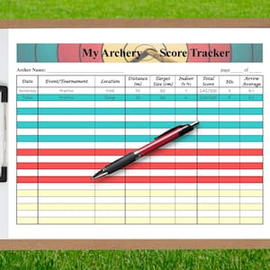 May include: A clipboard with an archery score tracker sheet. The sheet has a header that reads "My Archery Score Tracker". A black and red pen rests on the sheet. The background is green grass.