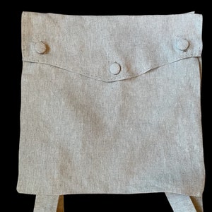 May include: A light gray linen bag with a flap and three buttons. The bag has two straps.