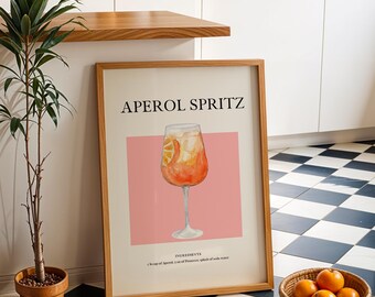 Pode incluir: Uma impressão emoldurada com uma ilustração em aquarela de um coquetel Aperol Spritz. A impressão tem um fundo rosa e o texto "APEROL SPRITZ" em letras pretas. Os ingredientes são listados abaixo da ilustração.