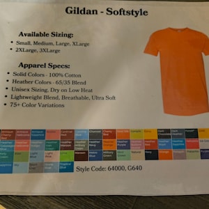 以下が含まれることがあります： オレンジ色のGildan Softstyle Tシャツが白い背景に表示されています。画像には、利用可能なサイズ、アパレル仕様、75色以上のカラーバリエーションの詳細が記載されたテキストが含まれています。スタイルコード：64000、G640。