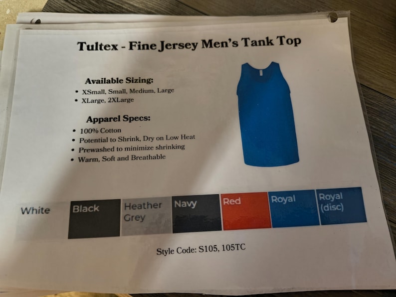 以下が含まれることがあります： 「Tultex - Fine Jersey Tank Top」の文字が入った白い紙に、青いタンクトップが写っています。紙には、利用可能なサイズ、アパレル仕様、白、黒、ヘザーグレー、ネイビー、赤、ロイヤルなどのカラーオプションも記載されています。