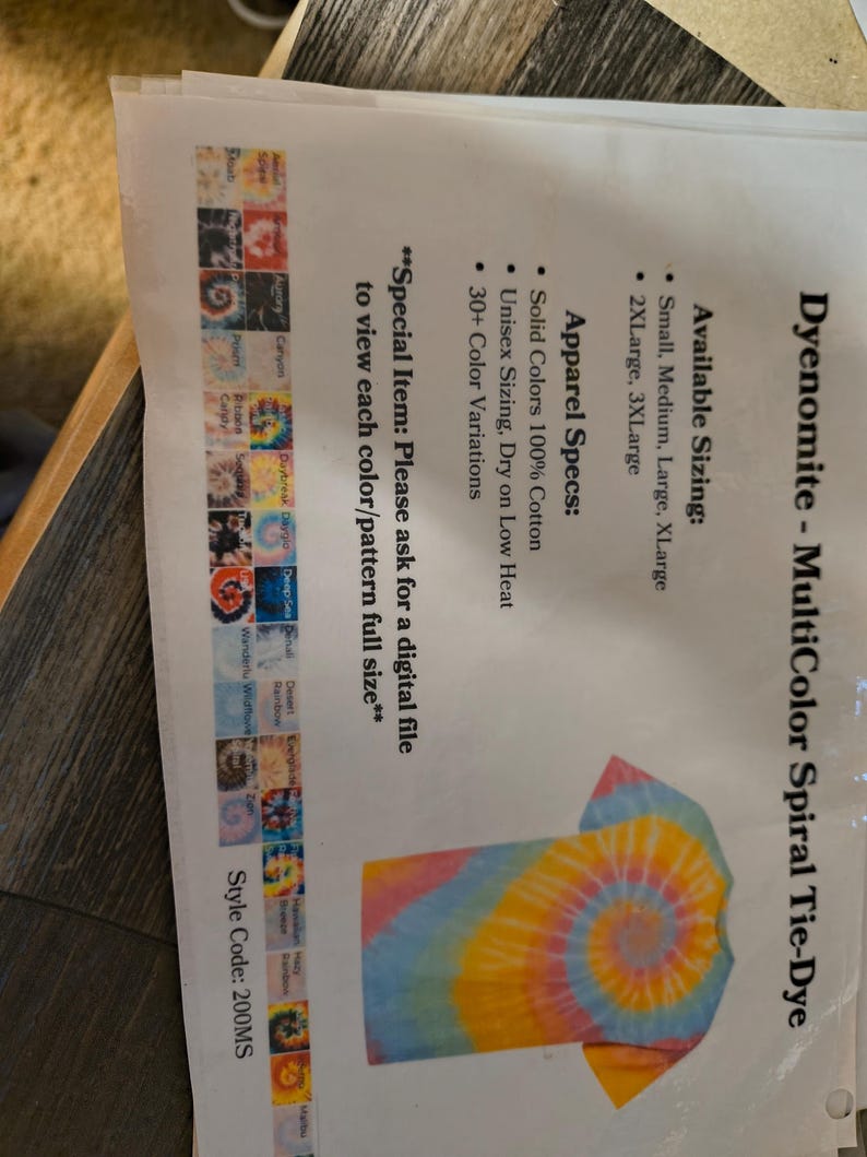 以下が含まれることがあります： Dyenomite MultiColor Spiral Tie-DyeのTシャツデザインが印刷されたシート。Tシャツは黄色、ピンク、青色のスパイラル模様です。サイズはSmallから3XLargeまで。シートには色のバリエーションも表示されています。