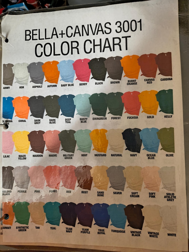 以下が含まれることがあります： Bella+Canvas 3001 Tシャツの色見本で、さまざまな色が表示されています。ArmyからWhiteまで、各色がサンプルTシャツで表現されています。「BELLA+CANVAS 3001 COLOR CHART」というテキストが上部にあります。
