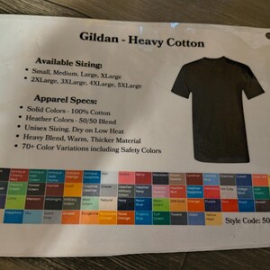 以下が含まれることがあります： 黒いTシャツのグラフィック、カラーサンプル、テキストが印刷されたシート。テキストには「Gildan - Heavy Cotton」、サイズオプション、アパレル仕様、スタイルコードが含まれています。カラーオプションには、白、黒、さまざまな色合いが含まれています。
