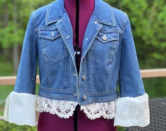 Upcycled denim jacket has added embroidered trim and vintage hand stitched ruffed sleeves.