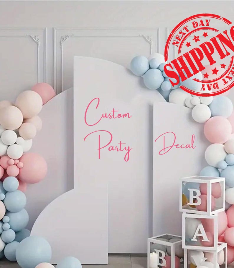 May include: A white arched backdrop display featuring the pink text Custom Party Decal, decorated with a cluster of light blue, white, and pale pink balloons, and stacked white transparent boxes containing balloons with letters B and A.