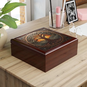 Könnte beinhalten: Eine dunkelbraune Holzbox mit einem dekorativen Deckel mit einem Baumdesign. Der Baum hat ein detailliertes, kompliziertes Muster mit einem Sonnenuntergangshintergrund. Die Box ist rechteckig mit glänzendem Finish, geeignet für Schmuck oder Andenken.