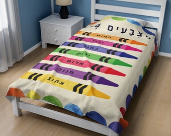 May include: A white twin-sized bedspread with a colorful crayon design. The crayons are arranged vertically and have Hebrew words written on them. The words are: "צהוב", "ירוק", "כחול", "סגול", "אדום", "כתום", "ורוד", "חום", "לבן".