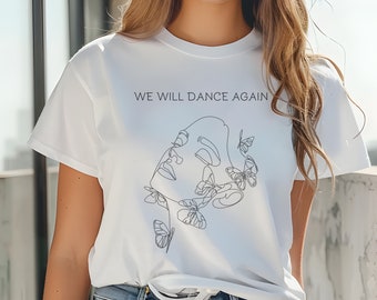 May include: White t-shirt featuring a line drawing of a woman's face with butterflies around her head. The text "WE WILL DANCE AGAIN" is printed on the shirt.