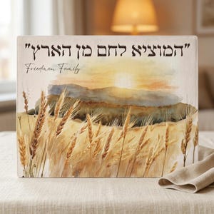May include: A rectangular challah cover featuring a watercolor illustration of a golden wheat field under a sunset sky. The Hebrew text "המוציא לחם מן הארץ" is printed in black at the top, with the custom text "Friedman Family" written below it.