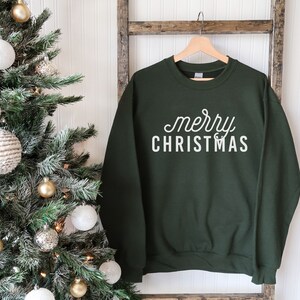 Op de afbeelding: Een donkergroen sweatshirt met de tekst "merry christmas" in witte letters.