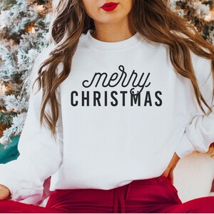 Op de afbeelding: Witte trui met de tekst "merry CHRISTMAS" in zwarte letters.