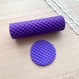 May include: A purple cylindrical rolling pin with a raised diamond grid texture and a matching flat purple circular disc featuring the same embossed diamond pattern, both designed for creating consistent impressions in soft crafting materials.
