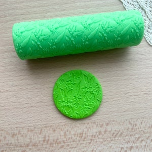 Può includere: Mattarello verde con un motivo floreale e un'impronta di pasta di zucchero verde abbinata.