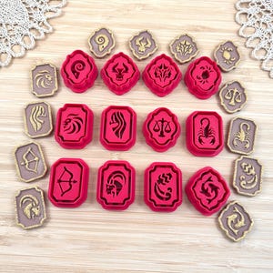 Può includere: Un set di dodici tagliabiscotti in plastica rosa brillante e dodici placche in rilievo color beige, ognuna raffigurante uno dei dodici segni zodiacali. Il set include i simboli di Ariete, Toro, Gemelli, Cancro, Leone, Vergine, Bilancia, Scorpione, Sagittario, Capricorno, Acquario e Pesci.