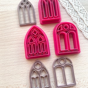 Puede incluir: Conjunto de seis cortadores de galletas con forma de ventanas arqueadas. Los cortadores están hechos de plástico rojo y marrón. Las ventanas tienen diferentes diseños, incluyendo una cruz, un círculo y un diamante.