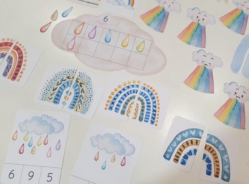 May include: A set of colorful rainbow and raindrop themed educational cards for children. The cards feature different patterns and designs, including polka dots, stripes, and geometric shapes. The cards also include numbers and counting activities.