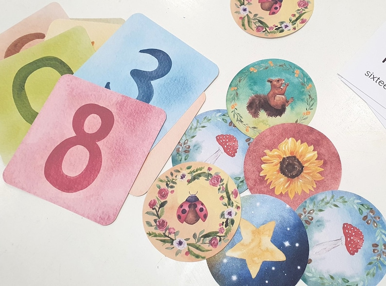 May include: A set of colorful cards with numbers and illustrations. The cards feature a ladybug, a sunflower, a squirrel, a mushroom, and a star. The cards are perfect for learning to count and for playing games.