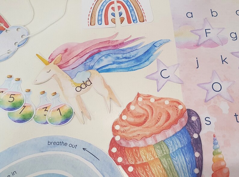 May include: A set of colorful educational flashcards featuring a unicorn, a cupcake, a rainbow, and letters of the alphabet. The unicorn is pink and blue with a white mane and tail. The cupcake is decorated with rainbow frosting and sprinkles. The rainbow is made of red, orange, yellow, green, blue, indigo, and violet. The letters are in a rainbow font.