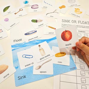 Könnte beinhalten: Lehrreiches Spiel mit Karten, die verschiedene Objekte wie einen Apfel, eine Glasflasche und eine Münze zeigen. Das Spiel heißt "Sink or Float?" und enthält eine Vorhersage- und Beobachtungstabelle.
