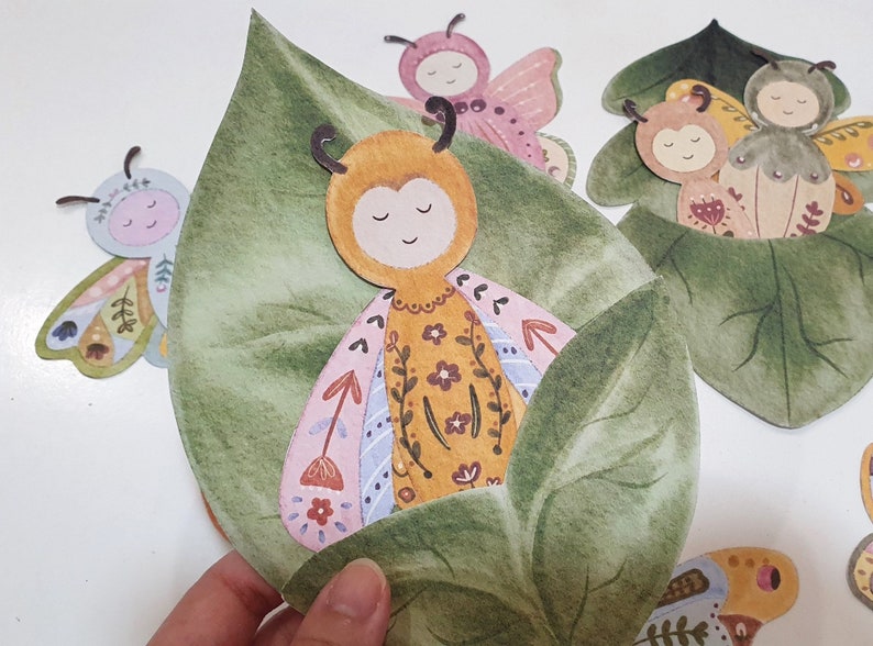 May include: A set of five paper cut-out butterflies with floral patterns and green leaves. The butterflies are in various colors, including pink, yellow, and blue. The butterflies are arranged in a cluster, with the leaves surrounding them.