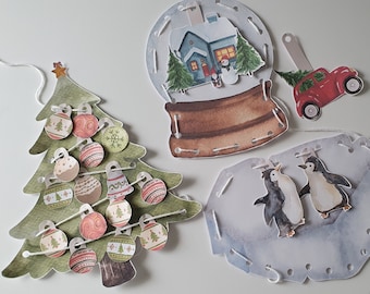 May include: Watercolor Christmas-themed paper cutouts. Includes a green Christmas tree with ornaments, a snow globe with a house, a red car with a Christmas tree, and two penguins. All pieces are connected with white string.