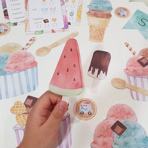 Puede incluir: Un conjunto de conos, bolas y toppings de helado de fieltro de colores para un juego de simulación de heladería. El conjunto incluye una rodaja de sandía, una paleta de chocolate y una cuchara.
