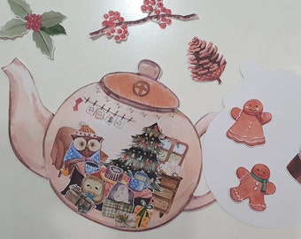 May include: A pink teapot with a brown lid and a white handle. The teapot is decorated with a Christmas tree, a window, and a fireplace. There are also two owls, a gingerbread man, and a pine cone.