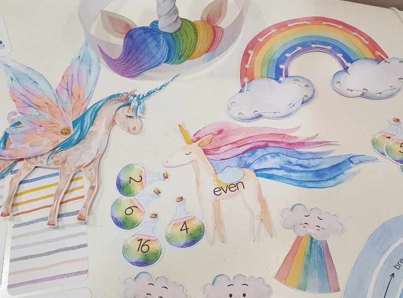 May include: A set of colorful felt unicorn and rainbow crafts for kids. The set includes a unicorn head, a rainbow, a unicorn with a rainbow mane, and a unicorn with wings. The set also includes a cloud with a rainbow and a set of potion bottles with numbers on them.