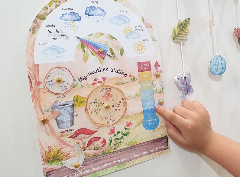 May include: A colorful weather station with a wooden frame and a variety of weather icons, including a sun, clouds, rain, and wind. The station also includes a thermometer with a sliding indicator to show the temperature. The text "My weather station" is printed on the station.