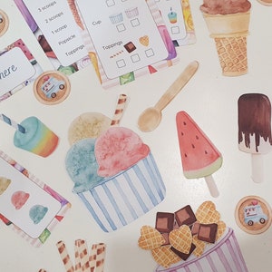 May include: A set of printable ice cream shop play food and order forms. The set includes ice cream cones, scoops, toppings, cups, and popsicles. The items are printed on white cardstock with watercolor illustrations.