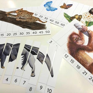 Może przedstawiać: Zestaw edukacyjnych pasków puzzli z akwarelowymi ilustracjami lamparta na kłodzie, motyli, mrówkojada i orangutana. Każdy pasek zawiera wydrukowane sekwencje liczbowe, takie jak 2, 5, 4, 6, 7, 8, 9, 10, 12, 15, 18, 21, 24, 27, 10, 20, 30, 40, 50, 60.