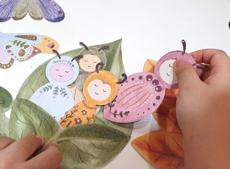 May include: A set of four felt butterfly figures with different colors and patterns. The butterflies are arranged on a green leaf with a brown leaf in the background.
