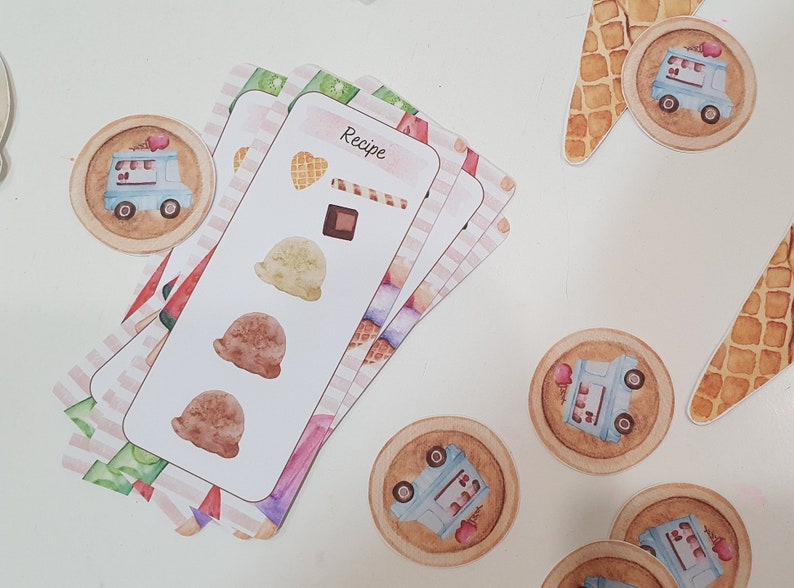 May include: A set of ice cream recipe cards with illustrations of ice cream scoops, cones, and a chocolate bar. The cards have a pink and white striped pattern and the word "Recipe" is printed on the top card.