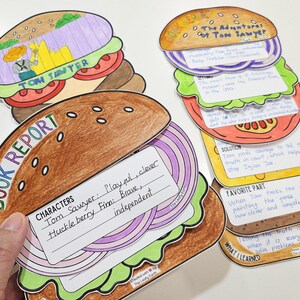 以下が含まれることがあります： 様々なテキストとイラストが描かれた、ハンバーガーの形をした手作りのカラフルな紙の切り抜き。 ハンバーガーをテーマにした切り抜きには、「Book Report」と「The Adventures of Tom Sawyer」と書かれており、手書きのメモが添えられています。