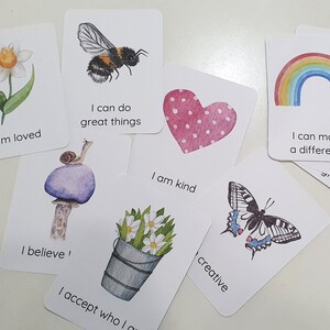 Puede incluir: Conjunto de tarjetas de afirmaci&oacute;n con ilustraciones de acuarela. Las tarjetas presentan mensajes positivos como "Soy amado", "Puedo hacer grandes cosas", "Soy amable", "Creo", "Acepto qui&eacute;n soy", "creativo", "Puedo marcar la diferencia".