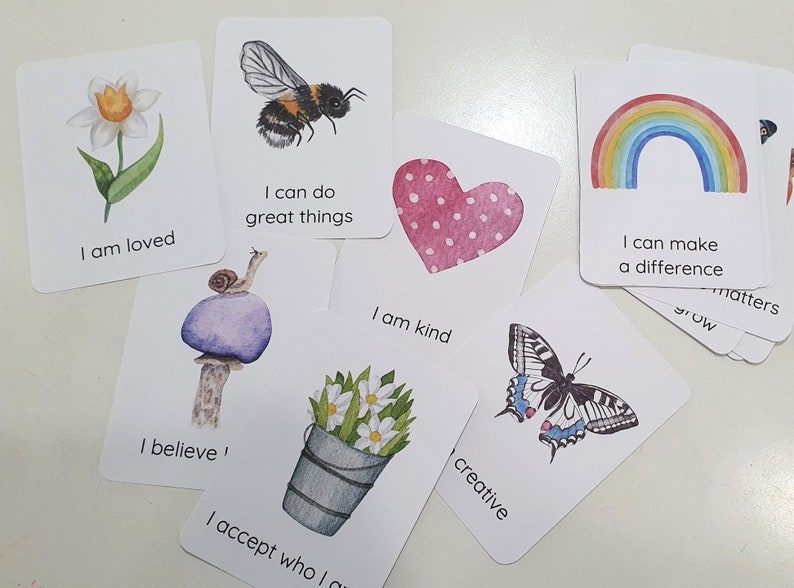 Puede incluir: Conjunto de tarjetas de afirmaci&oacute;n con ilustraciones de acuarela. Las tarjetas presentan mensajes positivos como "Soy amado", "Puedo hacer grandes cosas", "Soy amable", "Creo", "Acepto qui&eacute;n soy", "creativo", "Puedo marcar la diferencia".