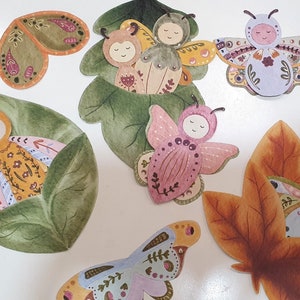 May include: A set of colorful hand-painted paper butterflies with intricate details. The butterflies are in various poses, some with wings open and some with wings closed. The butterflies are on a white background.