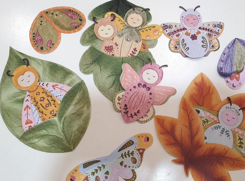 May include: A set of colorful hand-painted paper butterflies with intricate details. The butterflies are in various poses, some with wings open and some with wings closed. The butterflies are on a white background.