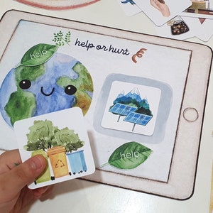 Può includere: Un gioco per bambini per imparare ad aiutare e danneggiare l'ambiente. Il gioco include carte con immagini di pannelli solari, bidoni della spazzatura e alberi. Le carte sono posizionate sullo schermo di un tablet con le parole "aiutare o danneggiare" e una Terra di cartoni animati.
