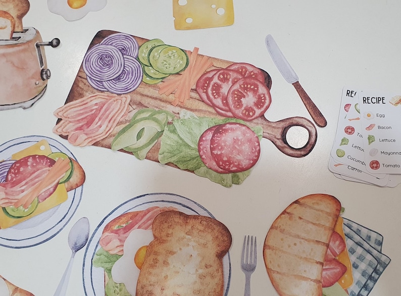 May include: A watercolor illustration of a sandwich recipe with ingredients on a wooden cutting board. The ingredients include lettuce, tomato, cucumber, bacon, and mayonnaise. The recipe cards list the ingredients in English.