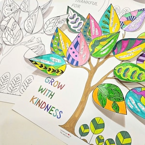 May include: A colorful paper craft featuring a tree with brown trunk and branches, and leaves in various colors. Some leaves are blank, while others have encouraging phrases. The words "GROW WITH KINDNESS" are written in rainbow colors.