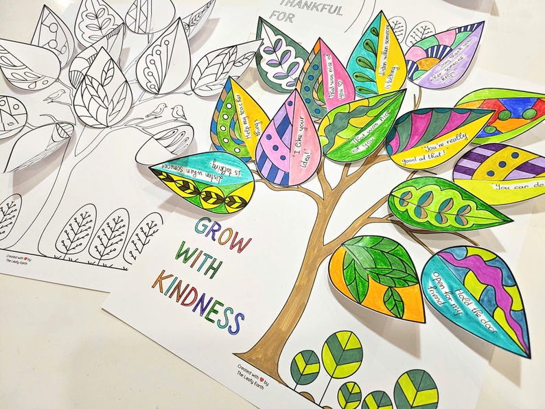 May include: A colorful paper craft featuring a tree with brown trunk and branches, and leaves in various colors. Some leaves are blank, while others have encouraging phrases. The words "GROW WITH KINDNESS" are written in rainbow colors.