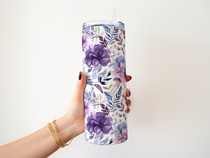 May include: A stainless steel tumbler with a floral pattern in shades of purple and blue. The tumbler has a lid and a straw.